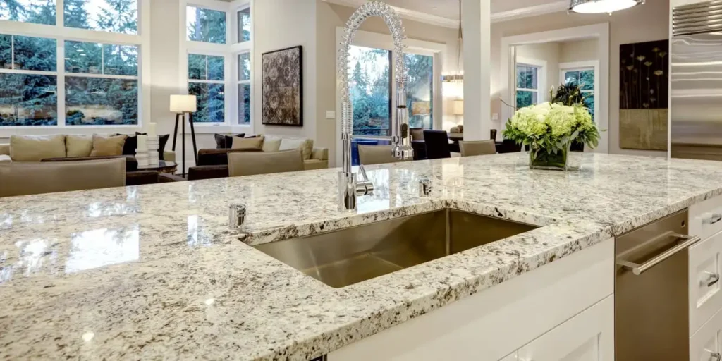 Modern kitchen with a large white and gray granite island featuring a stainless steel sink and faucet, showcasing leathered granite countertops perfect for homeowners asking, Is Leathered Granite Right For You?