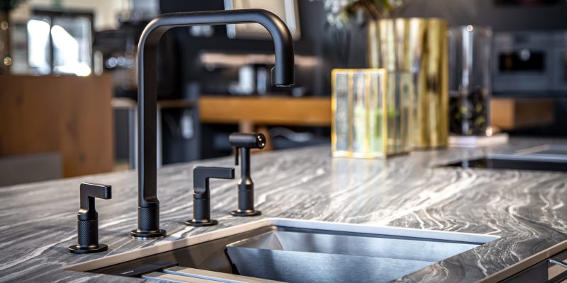 Black faucet with a steel sink in a stylish modern kitchen. Minimalism in refurbished apartment.